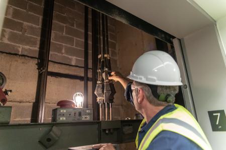 A construction worker checking cables in an elevator shaft.